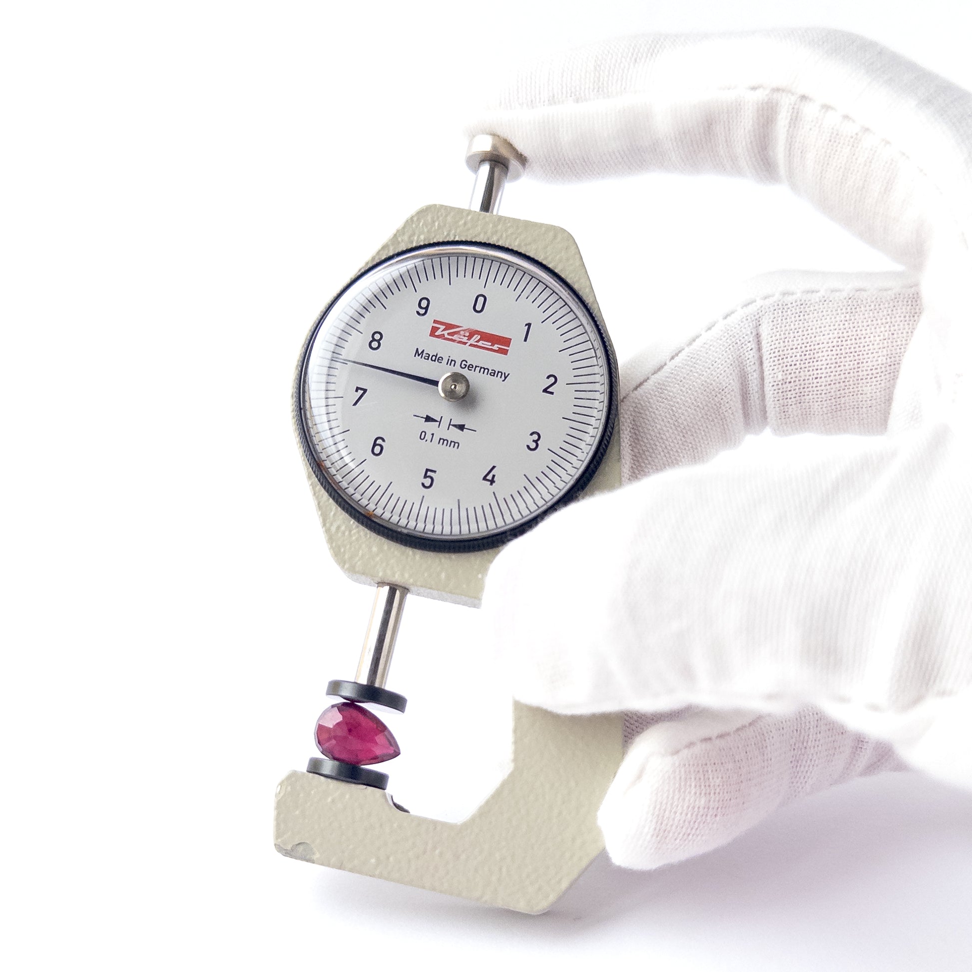 A dial gauge measures the Ruby pear‑cut cabochon 11mm × 7.4mm gemstone.