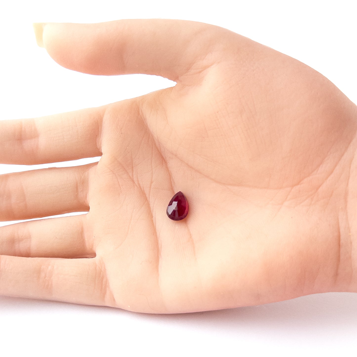 A person holds delicate pieces of Ruby cabochon, showcasing their pear‑cut design.