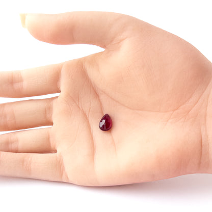 A person holds delicate pieces of Ruby cabochon, showcasing their pear‑cut design.