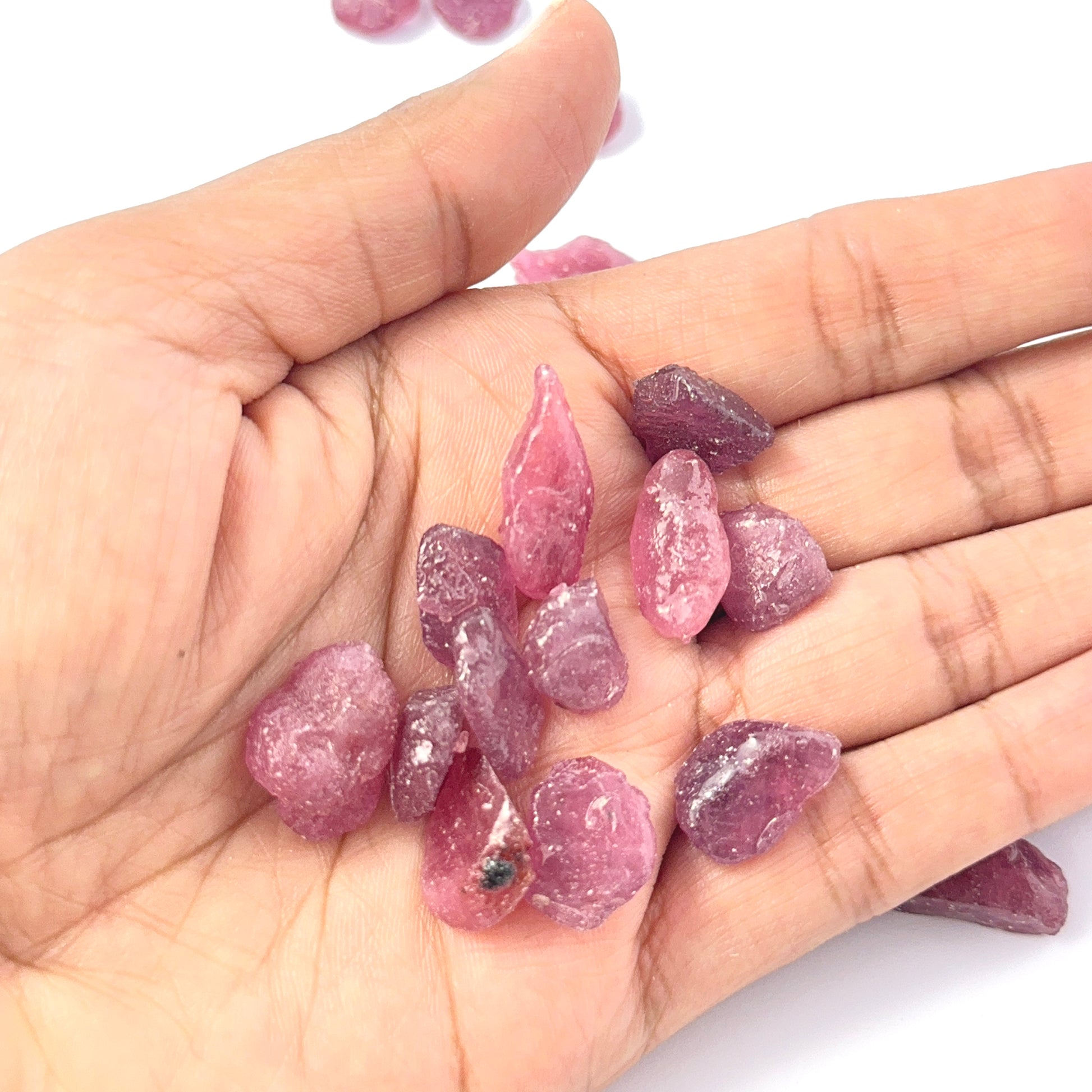 A person holds delicate pieces of Ruby rough, showcasing their natural rough design.