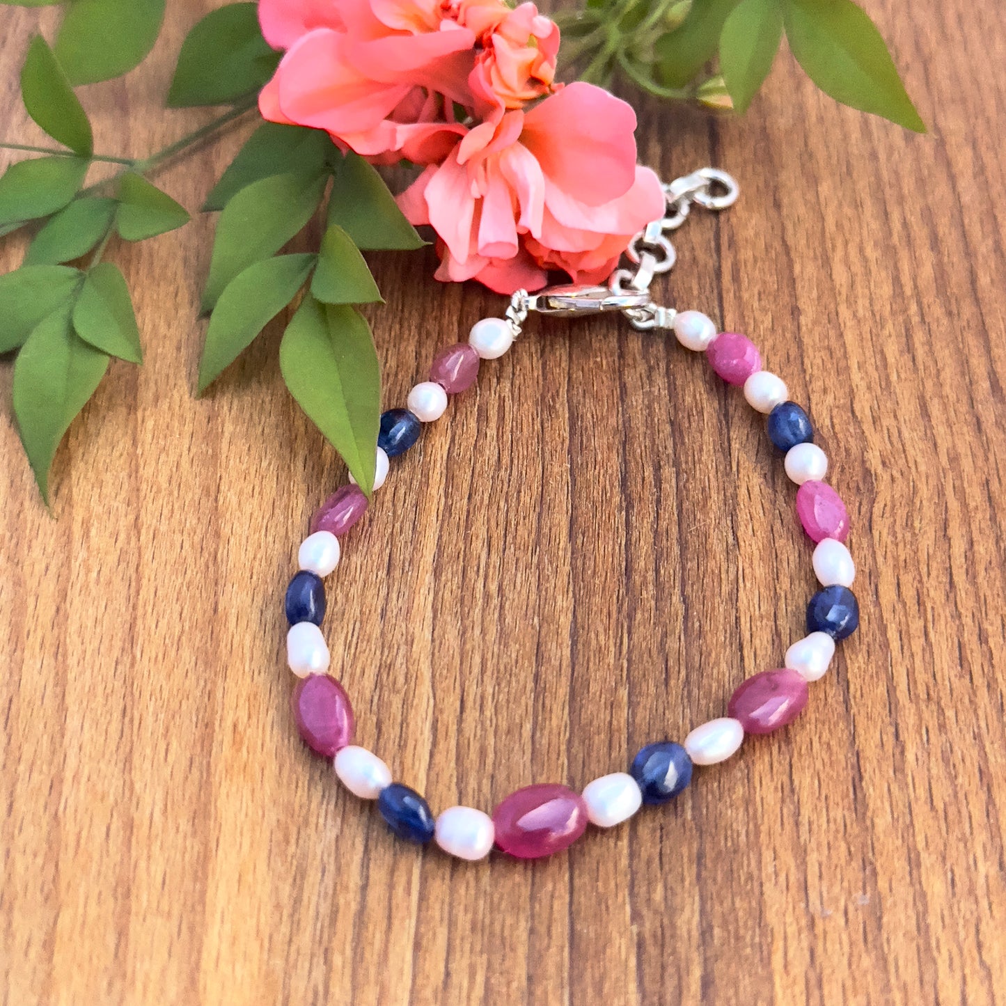 Close-up of smooth oval Ruby, Sapphire, and Pearl beads in a 19cm adjustable bracelet.