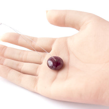 A person holds delicate pieces of Ruby beads, showcasing their smooth disc design.