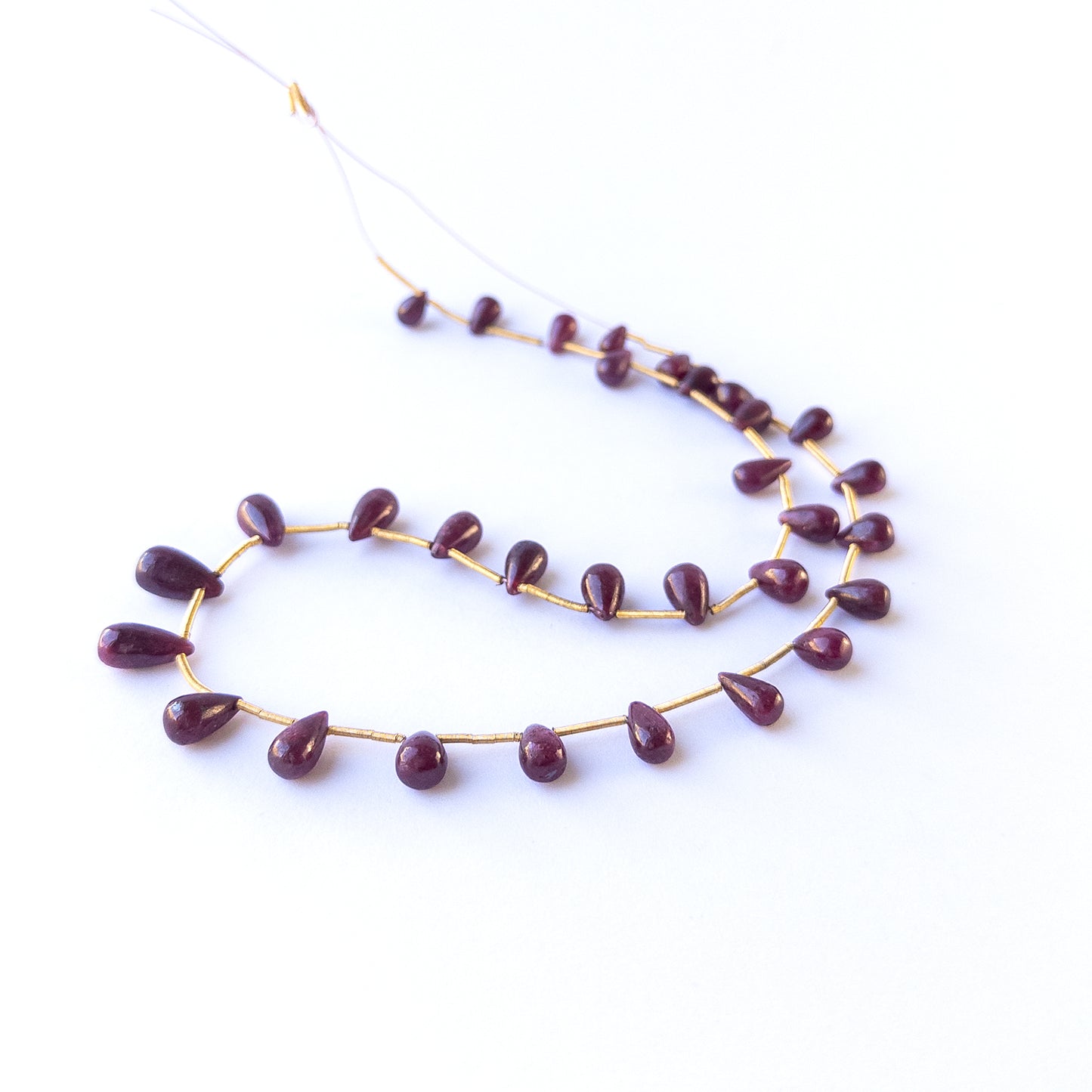 Handmade jewellery components with natural ruby smooth drop beads arranged in a 22‑piece set.