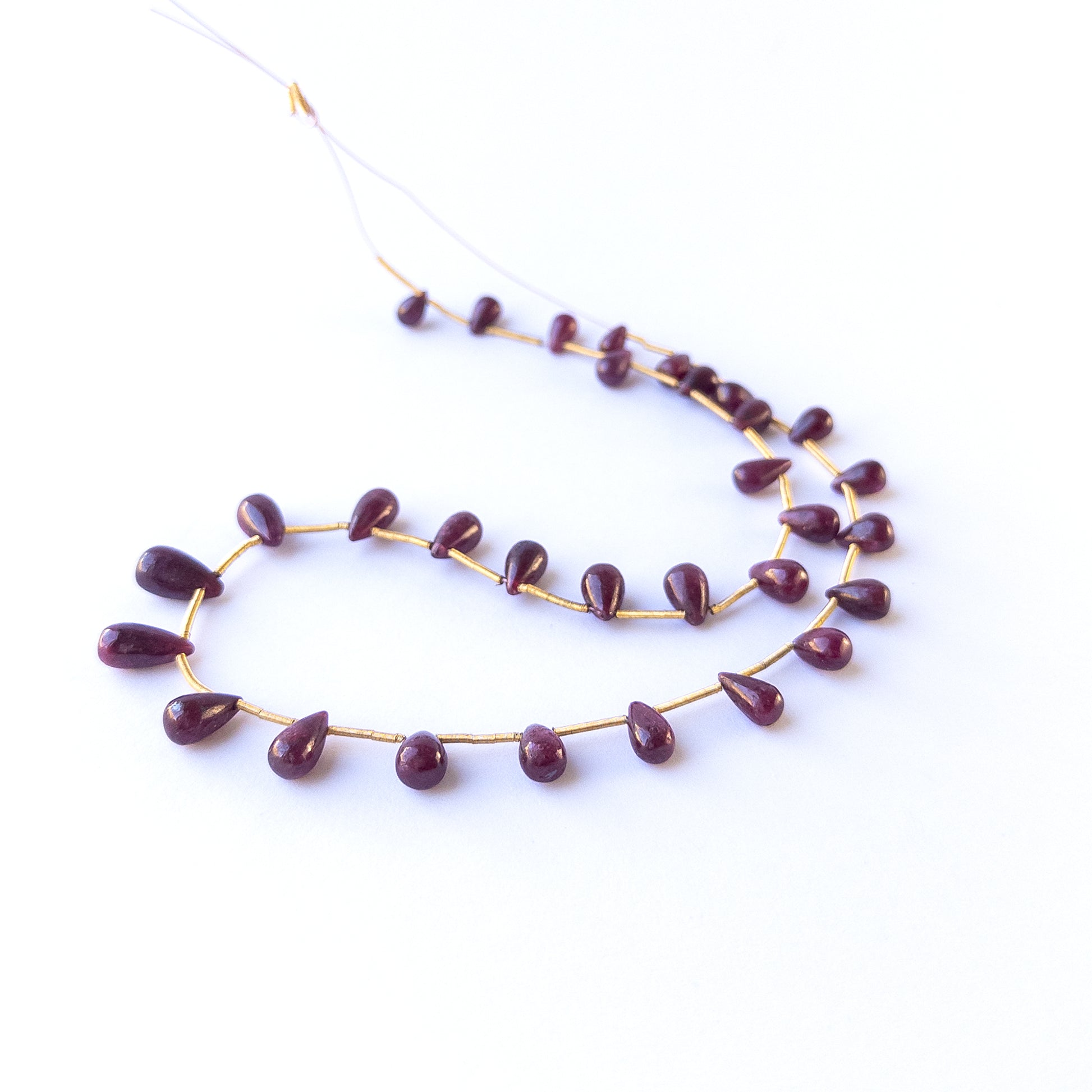 Handmade jewellery components with natural ruby smooth drop beads arranged in a 22‑piece set.