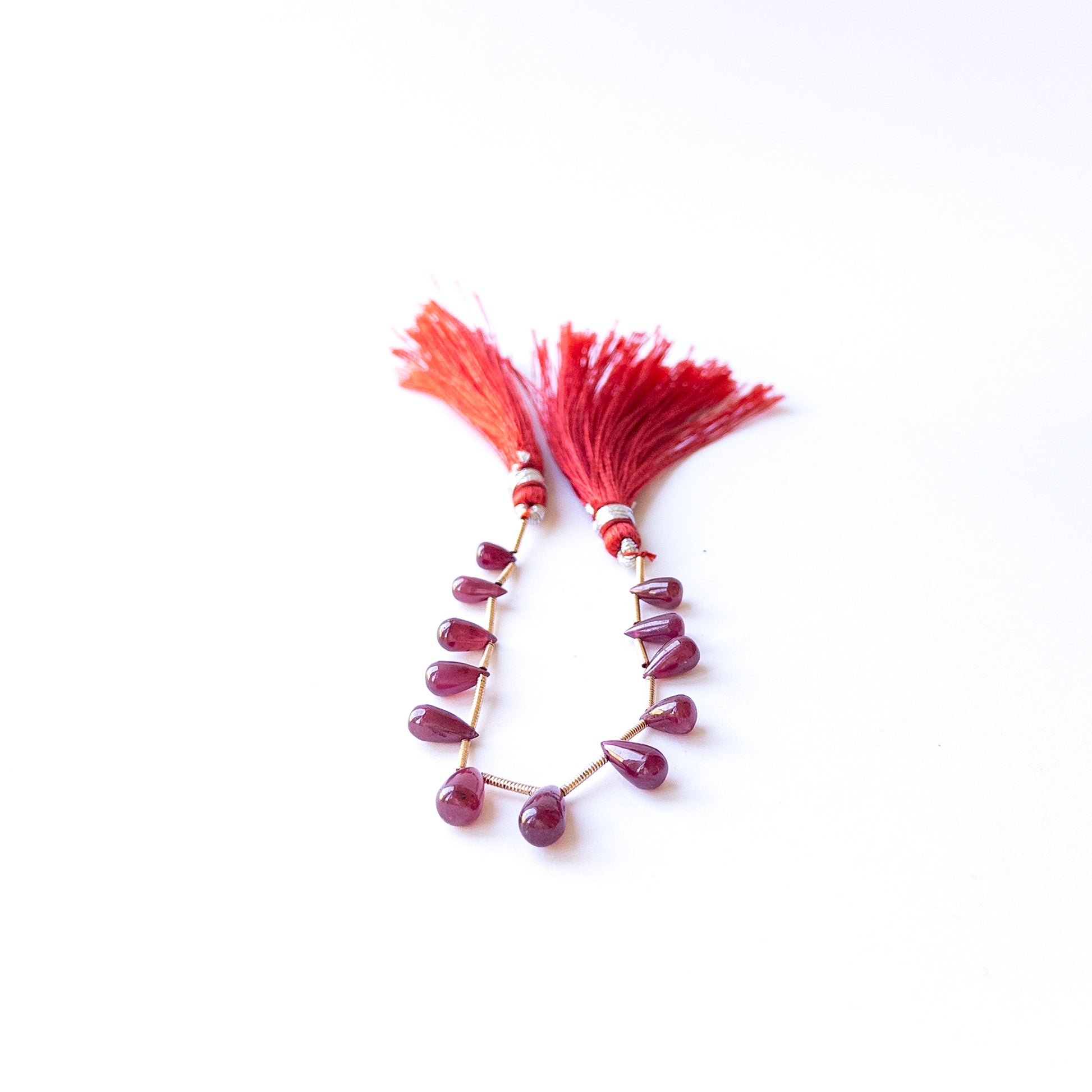 Genuine Ruby gemstone beads displaying deep red tones, polished surfaces, and beautifully shaped drops for jewellery design.