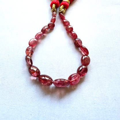 Close-up of Ruby gemstone beads with high-polish finish on smooth oval surfaces