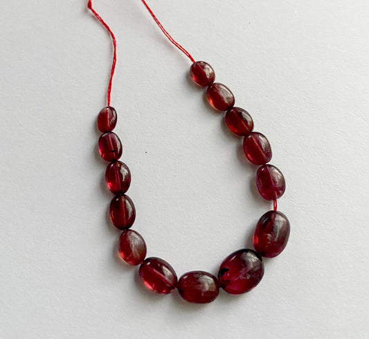 Ruby smooth oval beads in deep red tones, arranged in a 14-piece strand with polished finish.