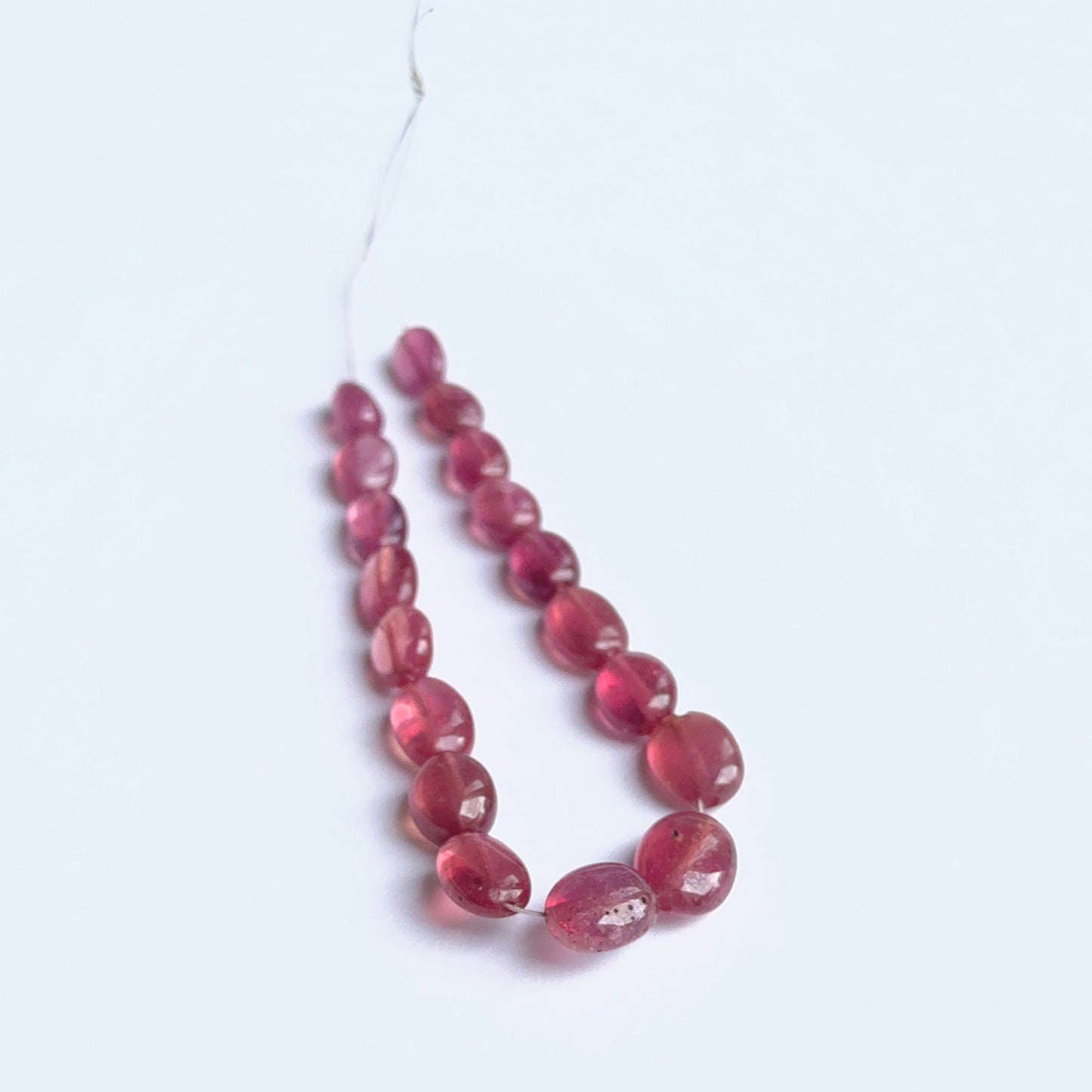 Ruby smooth oval gemstone beads showing rich red colour and glossy finish on a 36cm strand.