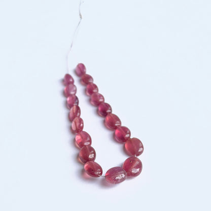 Ruby smooth oval gemstone beads showing rich red colour and glossy finish on a 36cm strand.