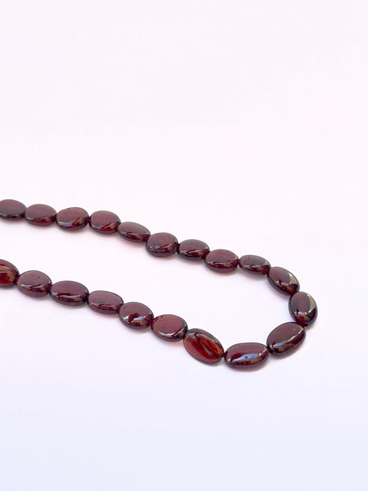 Close-up of ruby smooth oval 7.5–8.5mm x 6mm beads showing polished surface and deep crimson tones.