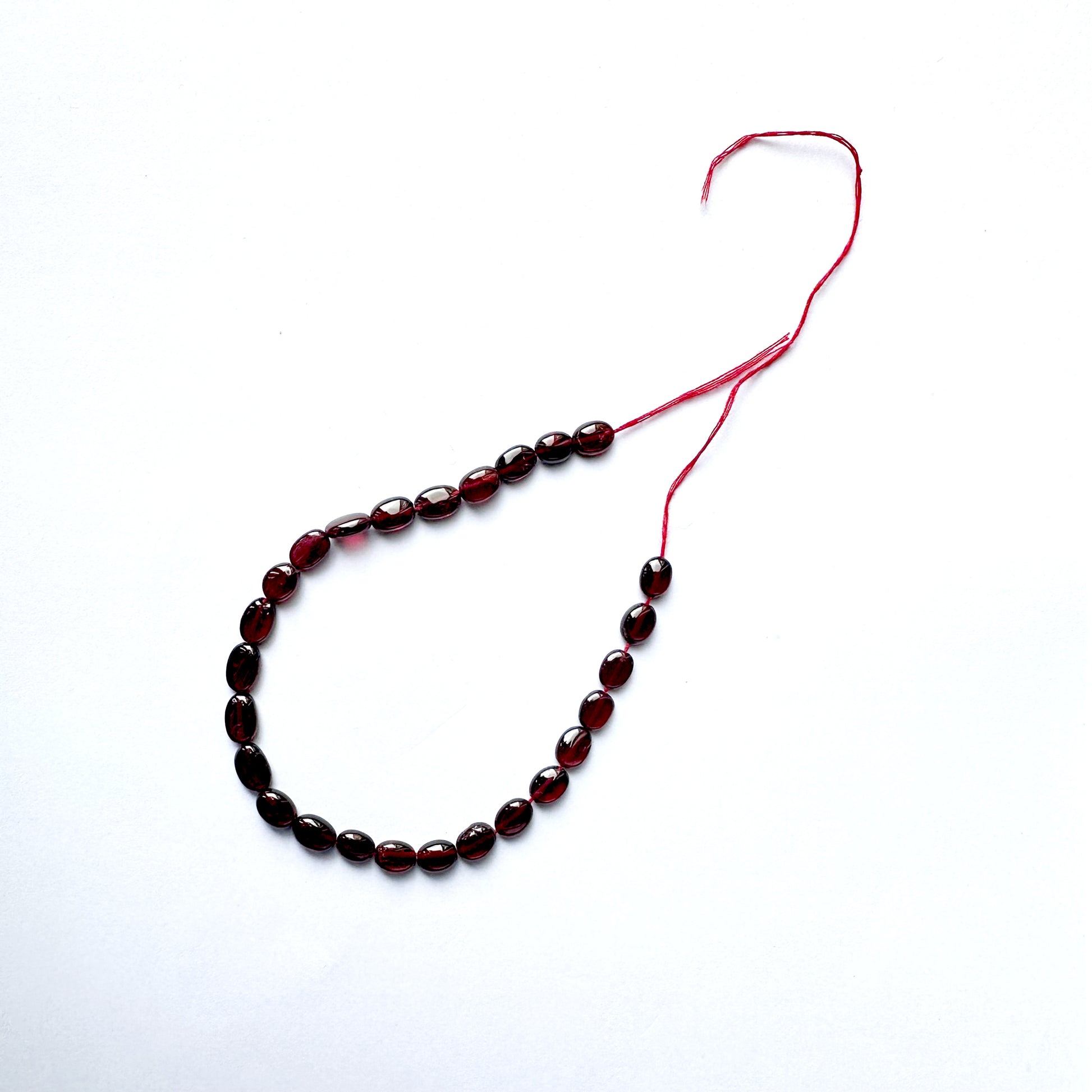 Ruby beads with consistent oval shape and radiant clarity across 26 pieces.