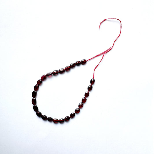 Ruby beads with consistent oval shape and radiant clarity across 26 pieces.