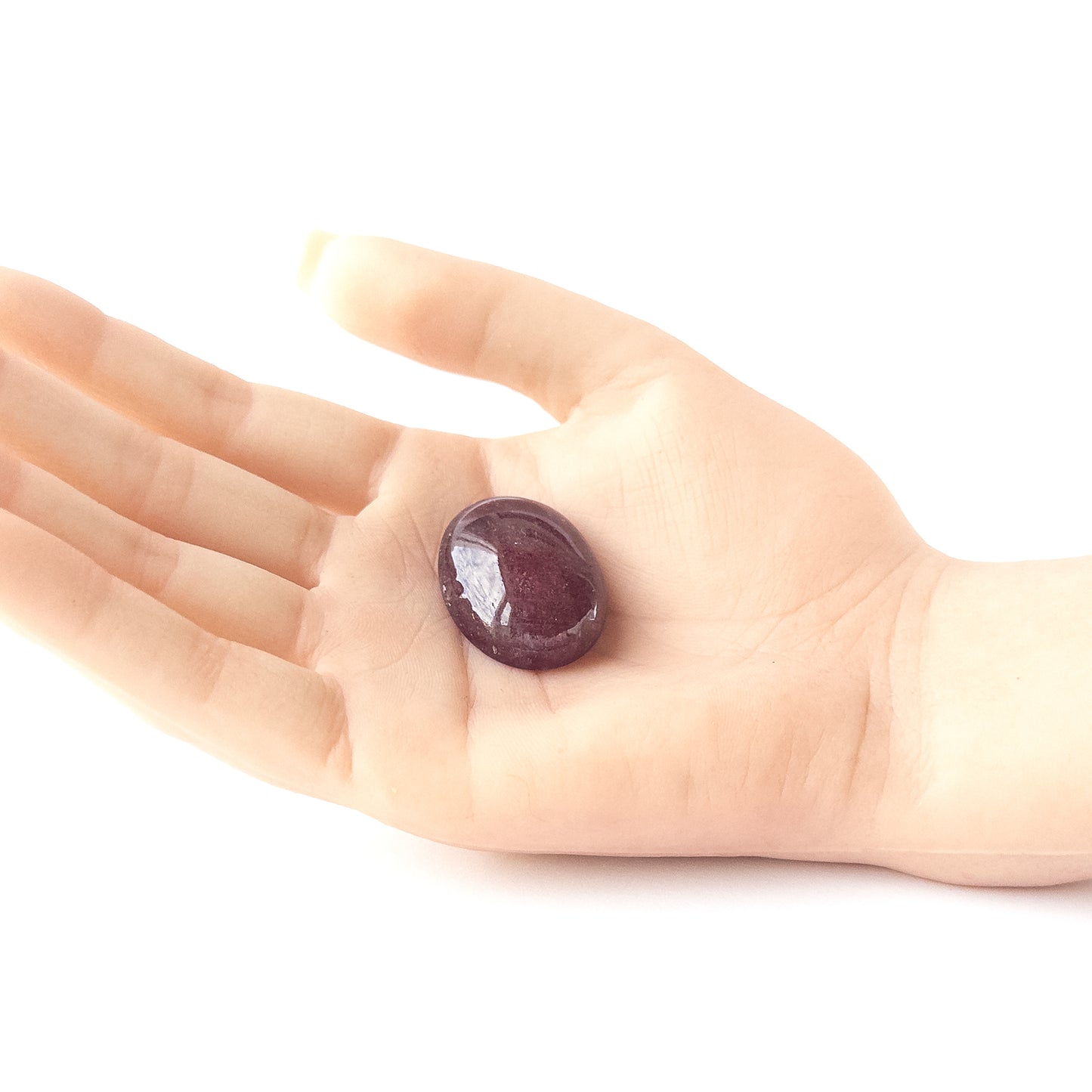 A person holds delicate pieces of Ruby cabochon, showcasing their smooth oval design.