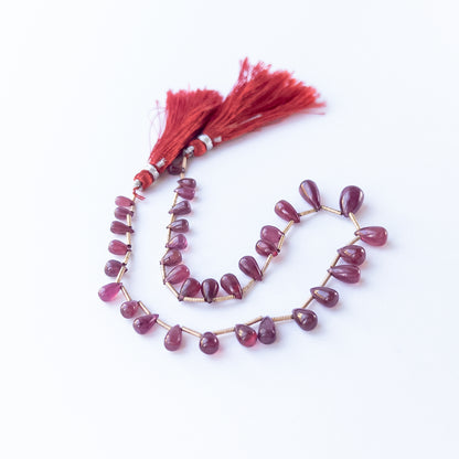 Ruby smooth briolette beads 3.1–7mm shown as a set of 34 pieces totalling 65 carats for jewellery making.