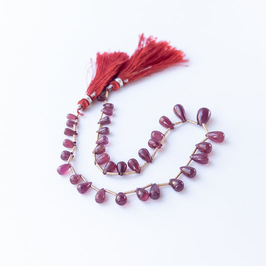 Ruby smooth briolette beads 3.1–7mm shown as a set of 34 pieces totalling 65 carats for jewellery making.