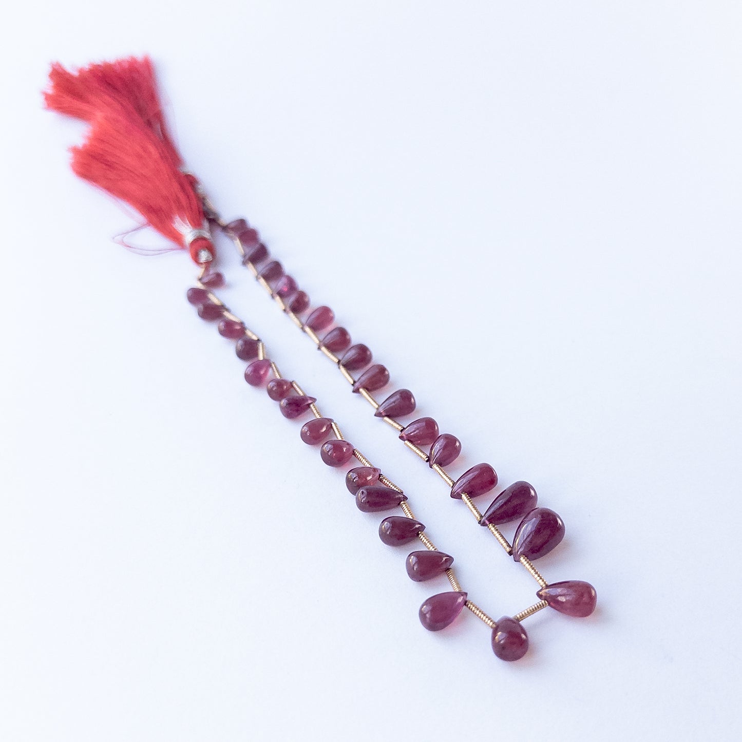 Ruby briolette beads, showing their polished teardrop shape and vibrant colour.