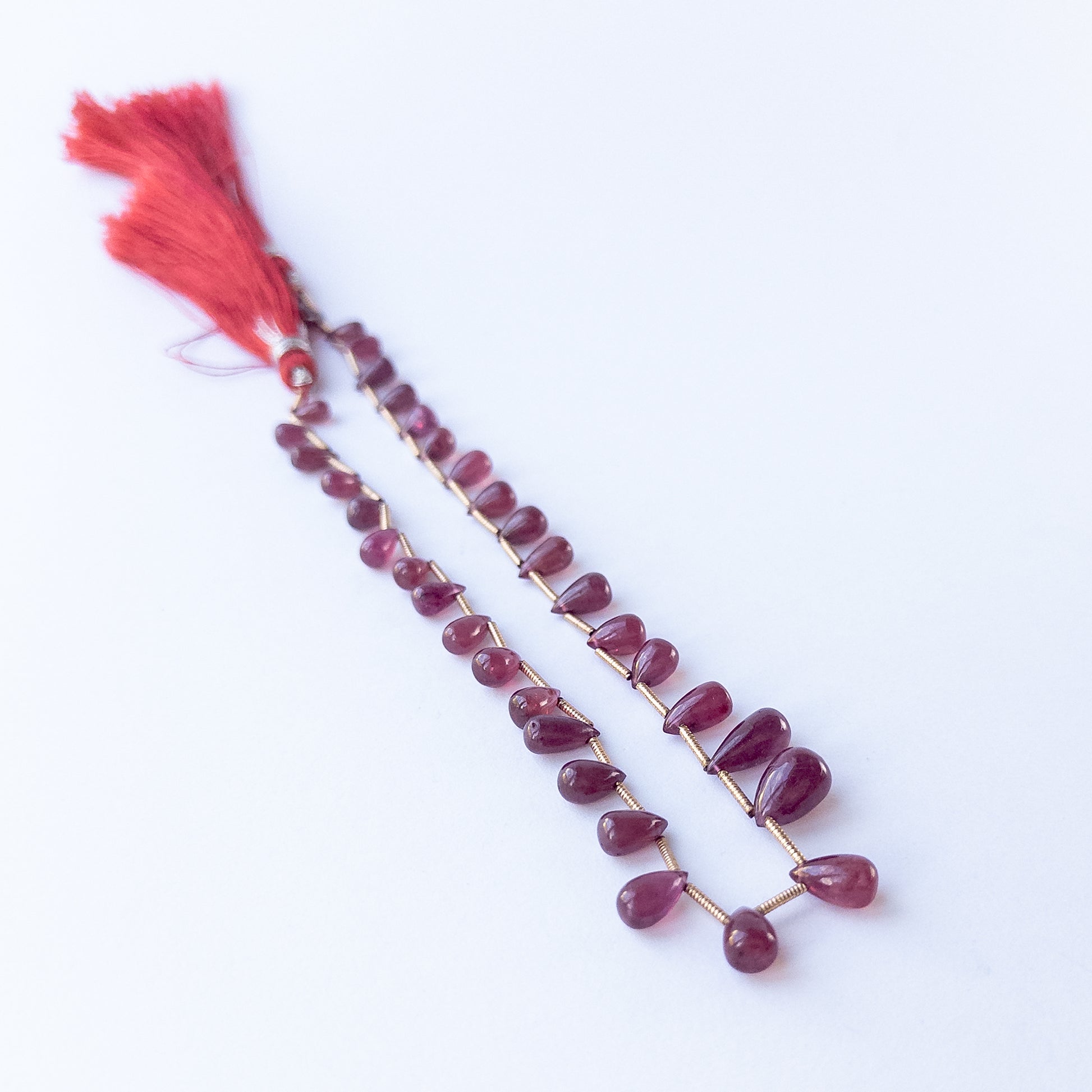 Ruby briolette beads, showing their polished teardrop shape and vibrant colour.