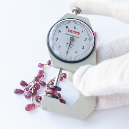 A dial gauge measures the Ruby smooth briolette 3.1–7mm gemstone. 