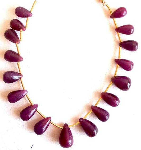 Ruby beads in teardrop shape arranged in a 17-piece set with glossy shine and elegant symmetry.