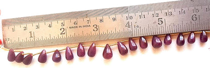 A ruler measures the ruby smooth teardrop gemstone for precision and quality control.