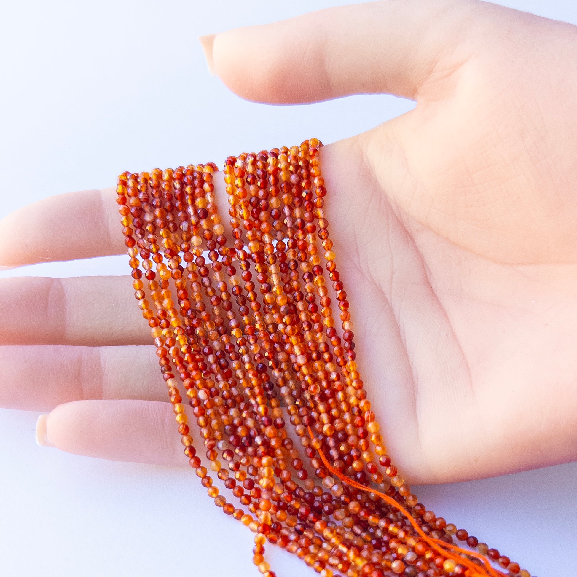 A person holds delicate strands of Rutile beads, showcasing their faceted rondelle design.