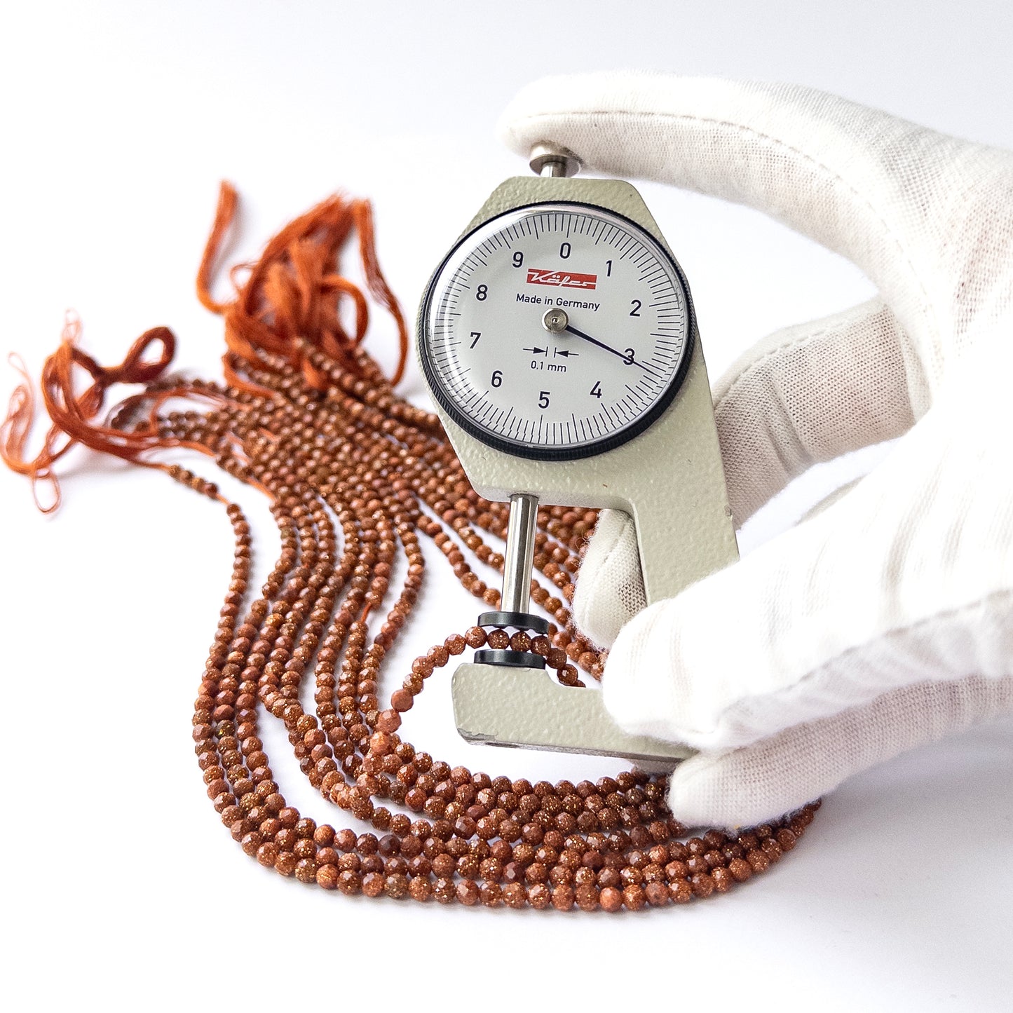 A dial gauge measures the Sandstone faceted rondelle 3–3.2mm gemstone.