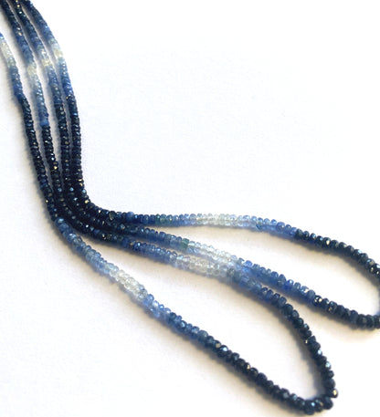 Gradient sapphire rondelle gemstones with high clarity and polished finish in cool blue hues.