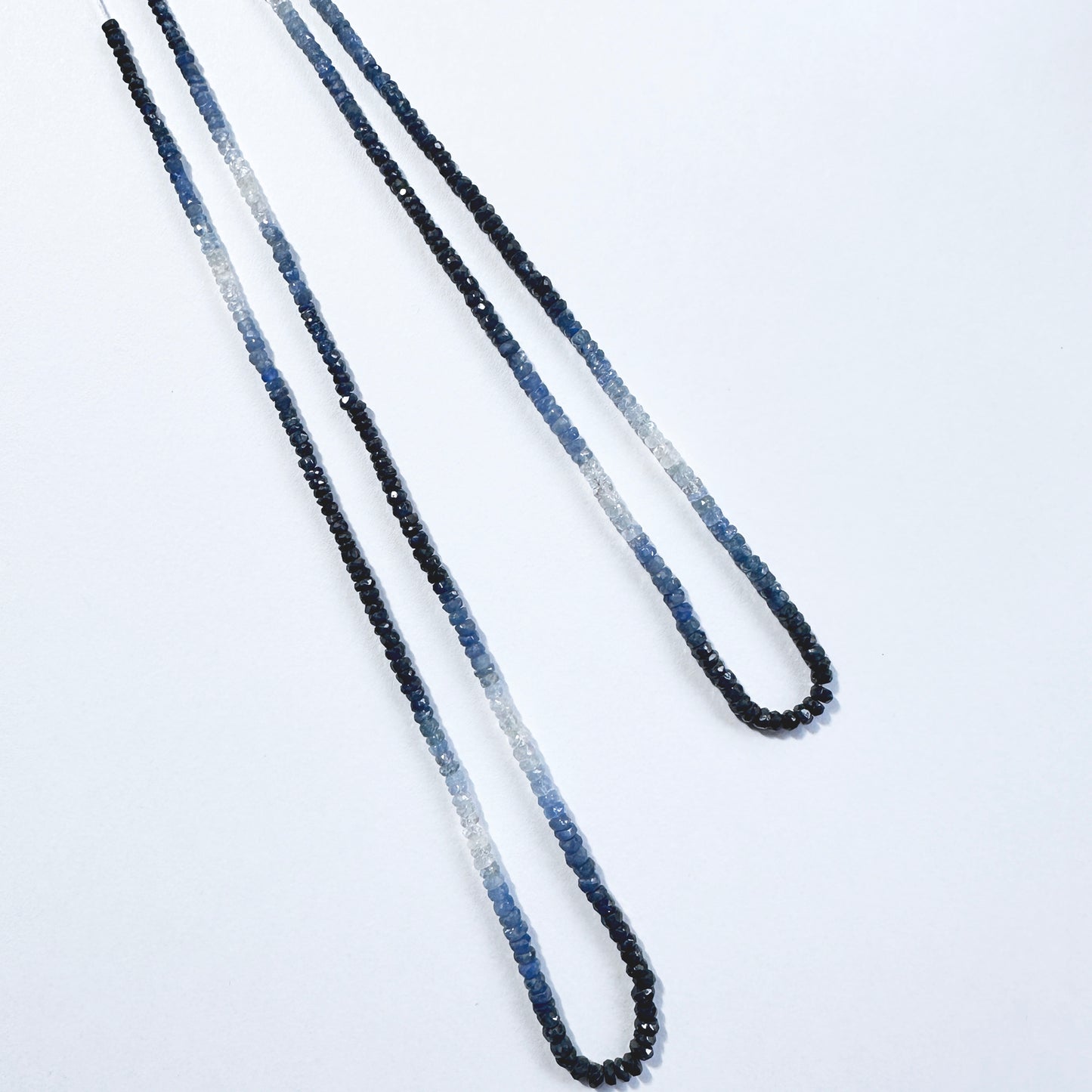 Gradient blue sapphire rondelle beads with faceted surfaces reflect light beautifully across the full strand.