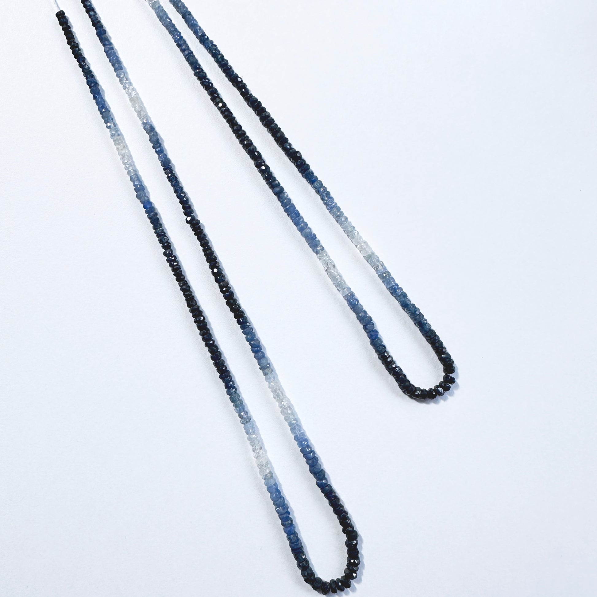 Gradient blue sapphire rondelle beads with faceted surfaces reflect light beautifully across the full strand.