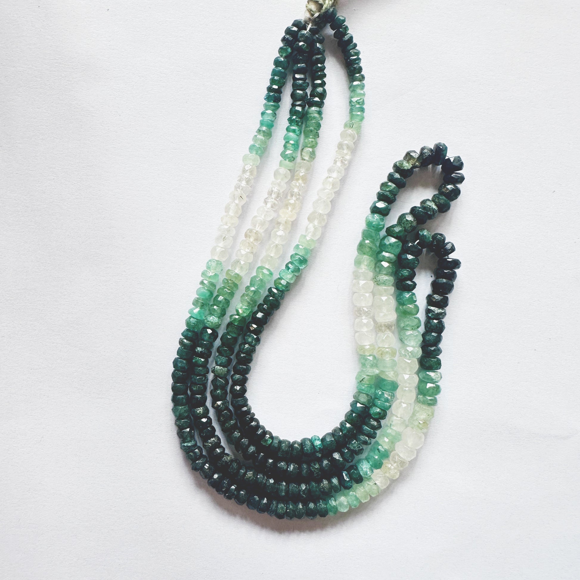 41cm strand of faceted Emerald beads arranged by size, exhibiting deep green brilliance.