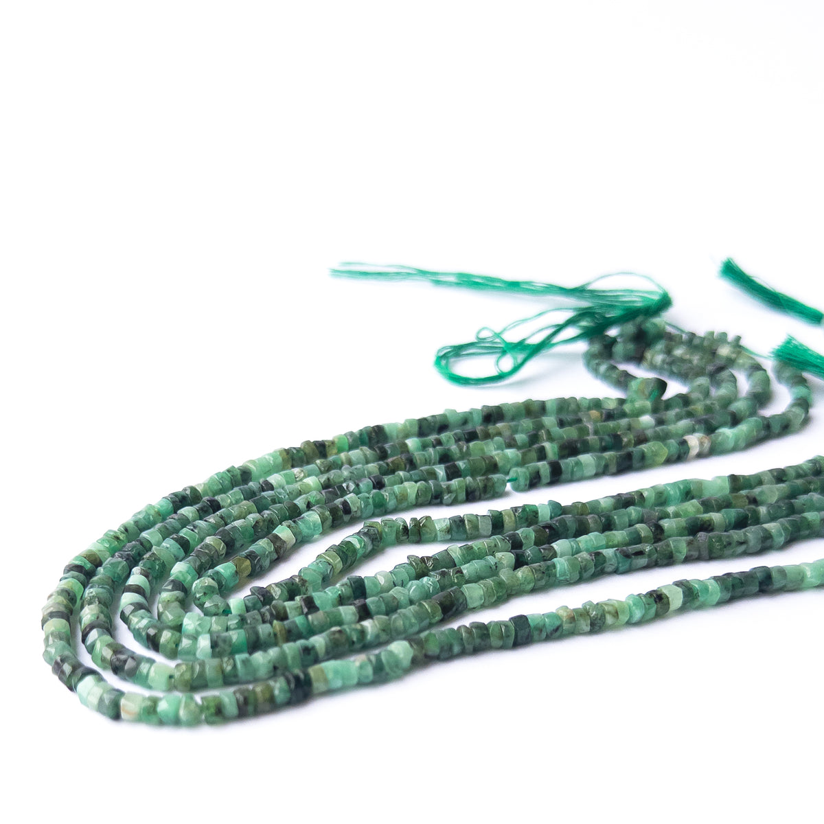 Close‑up of Shaded Emerald Smooth Wheel Heishi beads revealing shine, shape and craftsmanship.