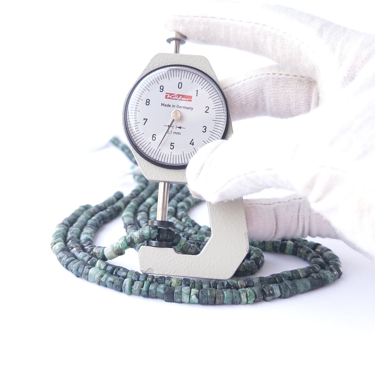 A dial gauge measures the Shaded Emerald smooth wheel 5.5mm gemstone.