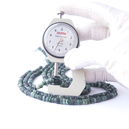 A dial gauge measures the Shaded Emerald smooth wheel 5.5mm gemstone.