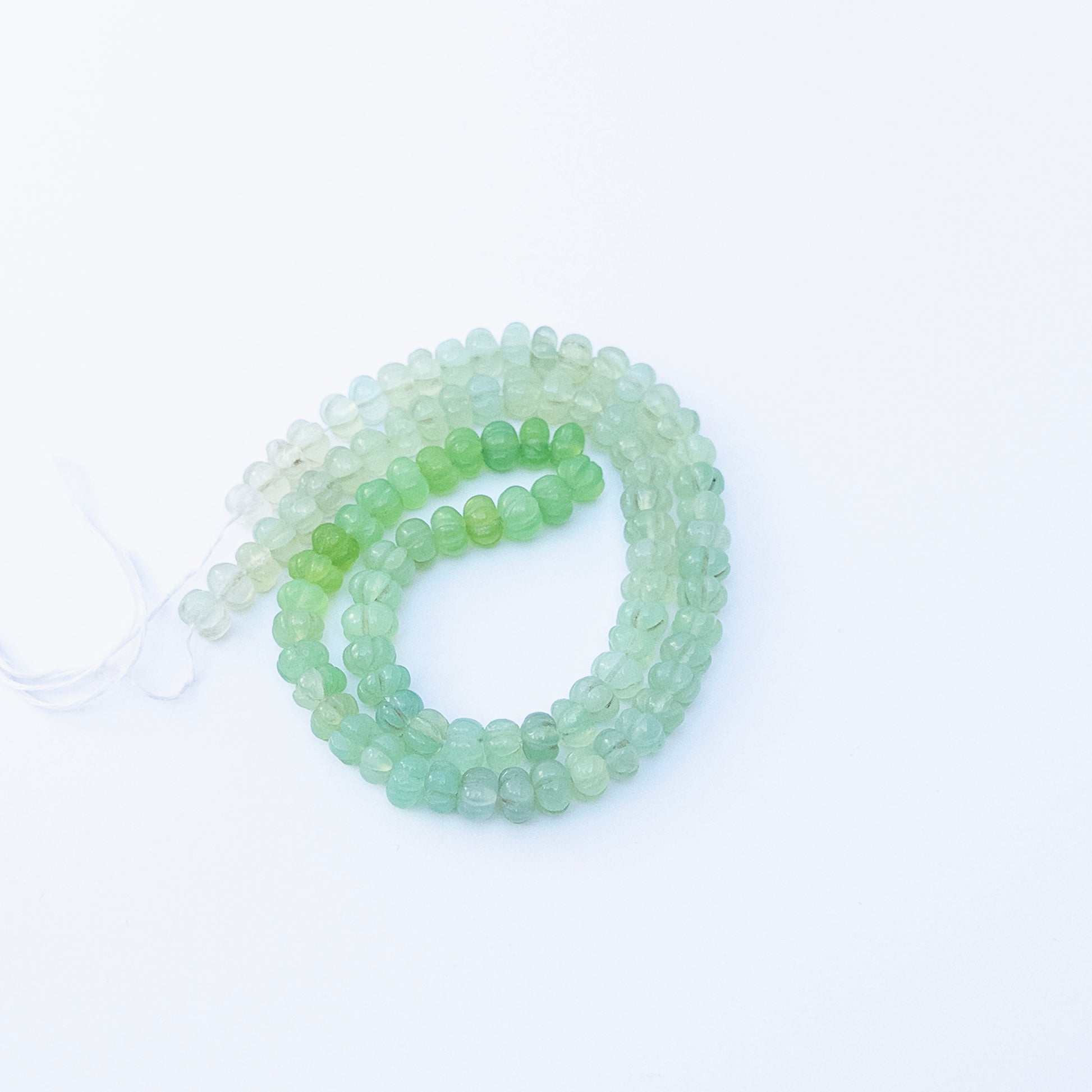 Close‑up of Shaded Green Chalcedony pumpkin cut beads highlighting their glossy finish and gradient green hues.