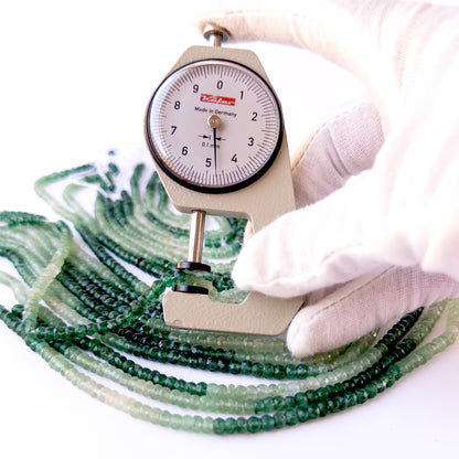 A dial gauge measures the Shaded Green Quartz faceted rondelle 4–4.5mm gemstone.
