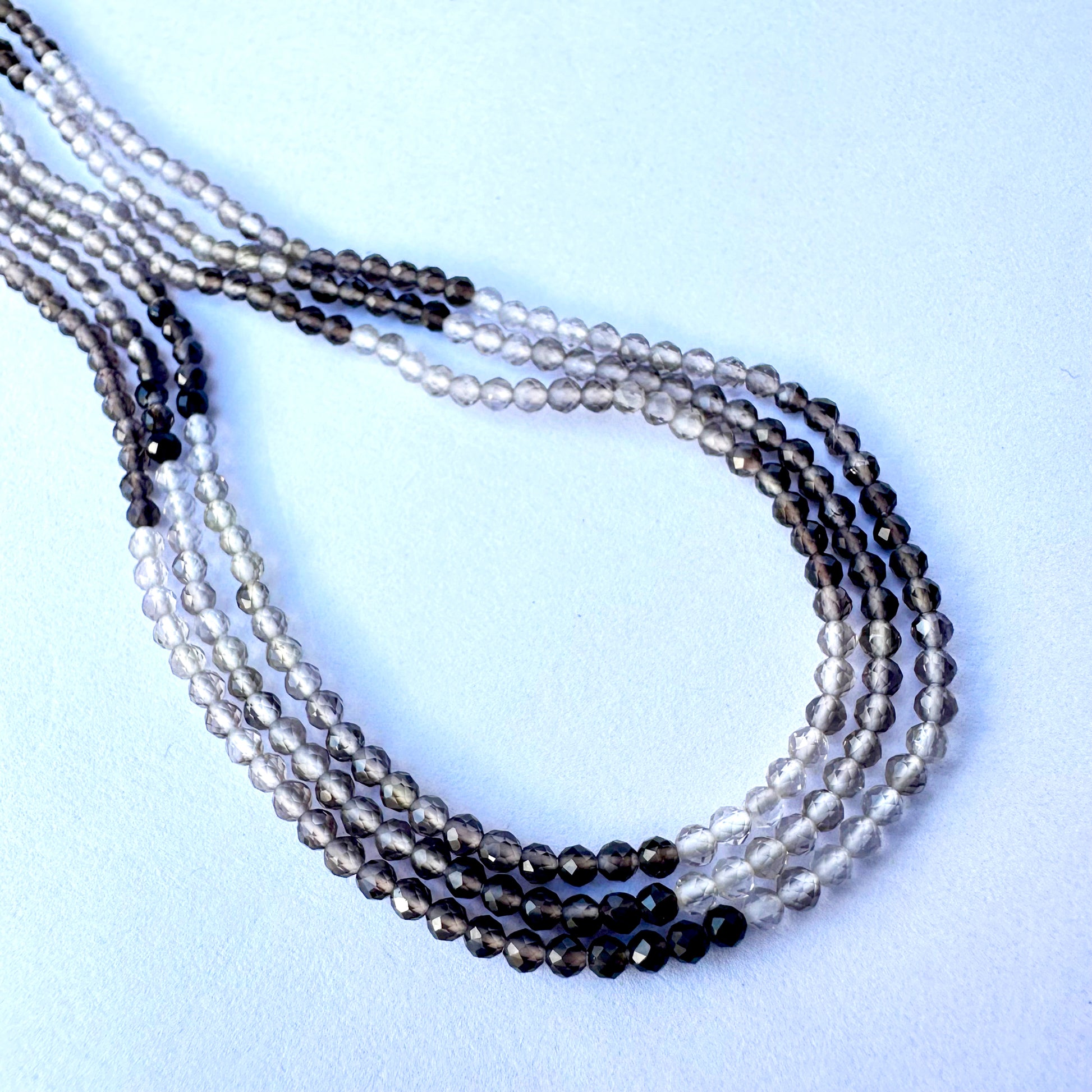 Close-up of smoky quartz beads showing shaded tones and sparkling faceted surfaces.