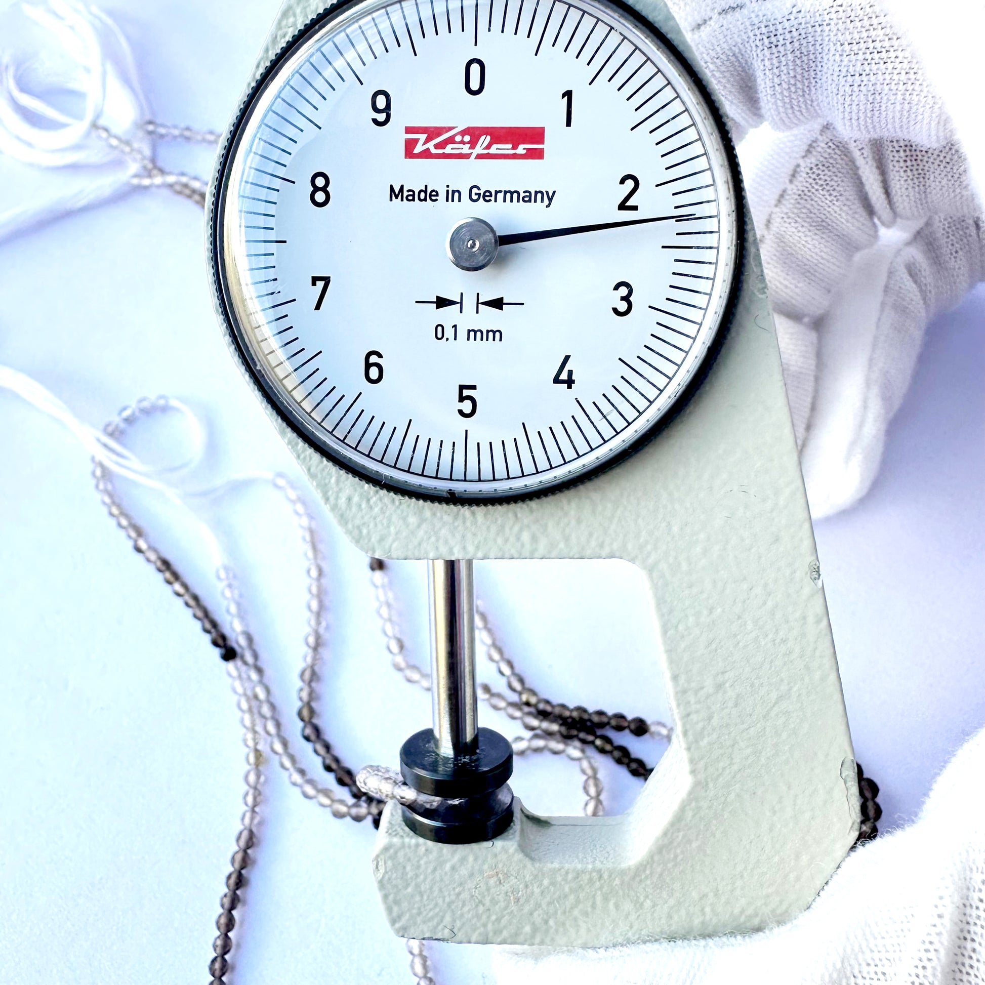A dial gauge measures the smoky quartz rondelle 2.2mm gemstone.