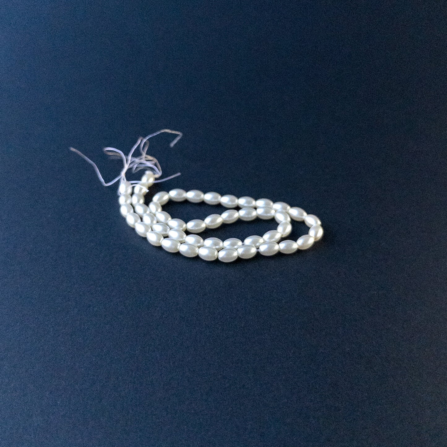 Close‑up of Shell Pearl gemstone beads in smooth oval shape with polished, glossy finish.