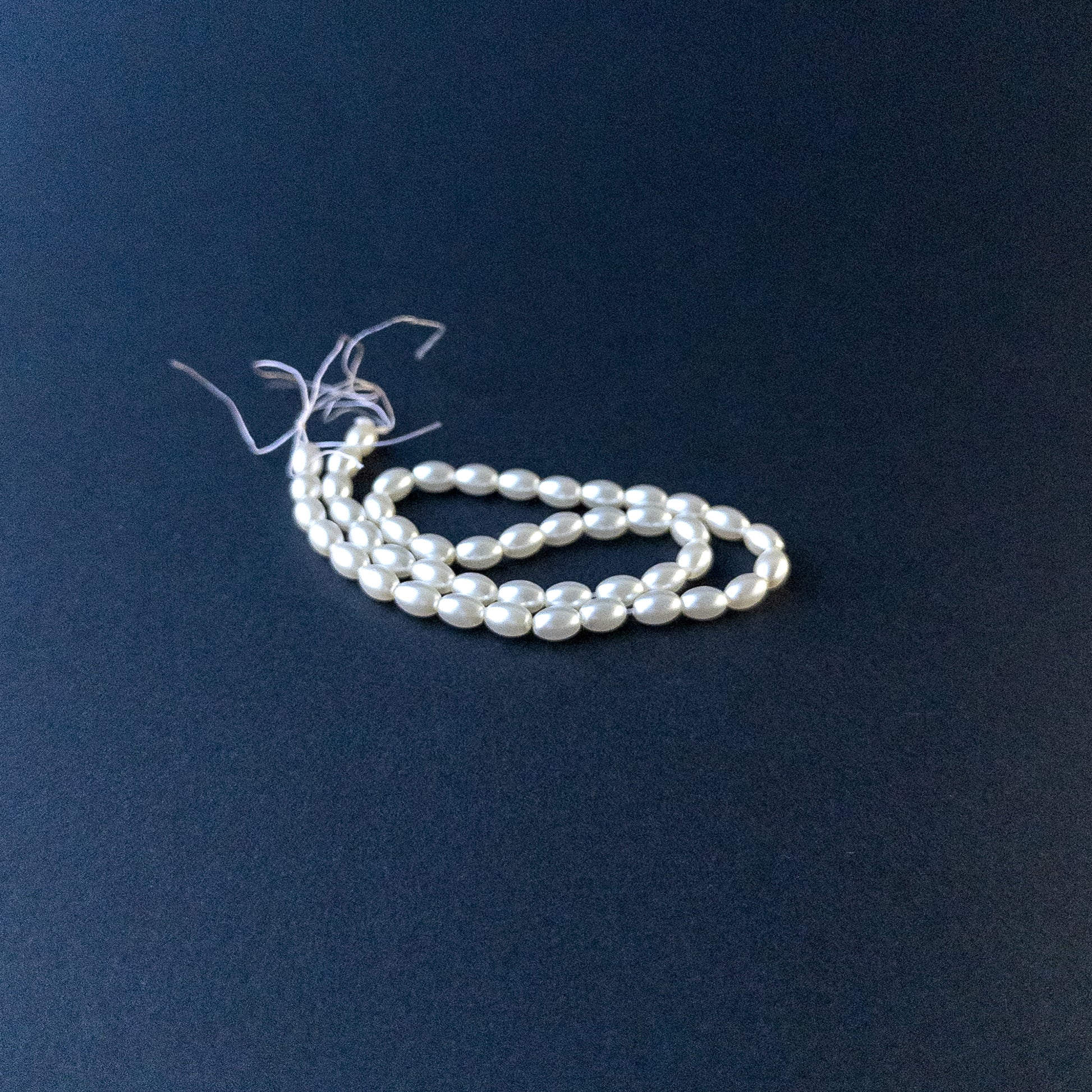 Close‑up of Shell Pearl gemstone beads in smooth oval shape with polished, glossy finish.