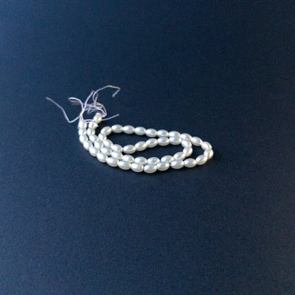 Close‑up of Shell Pearl gemstone beads in smooth oval shape with polished, glossy finish.