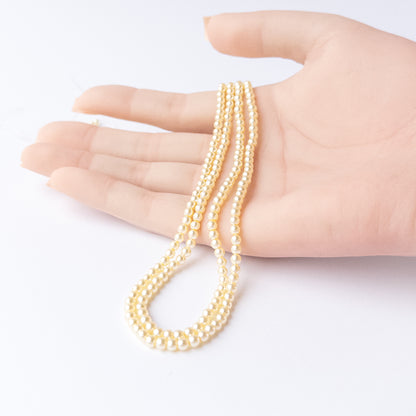 A video person holds delicate strands of Shell Pearl beads, showcasing their smooth round design and sparkle.