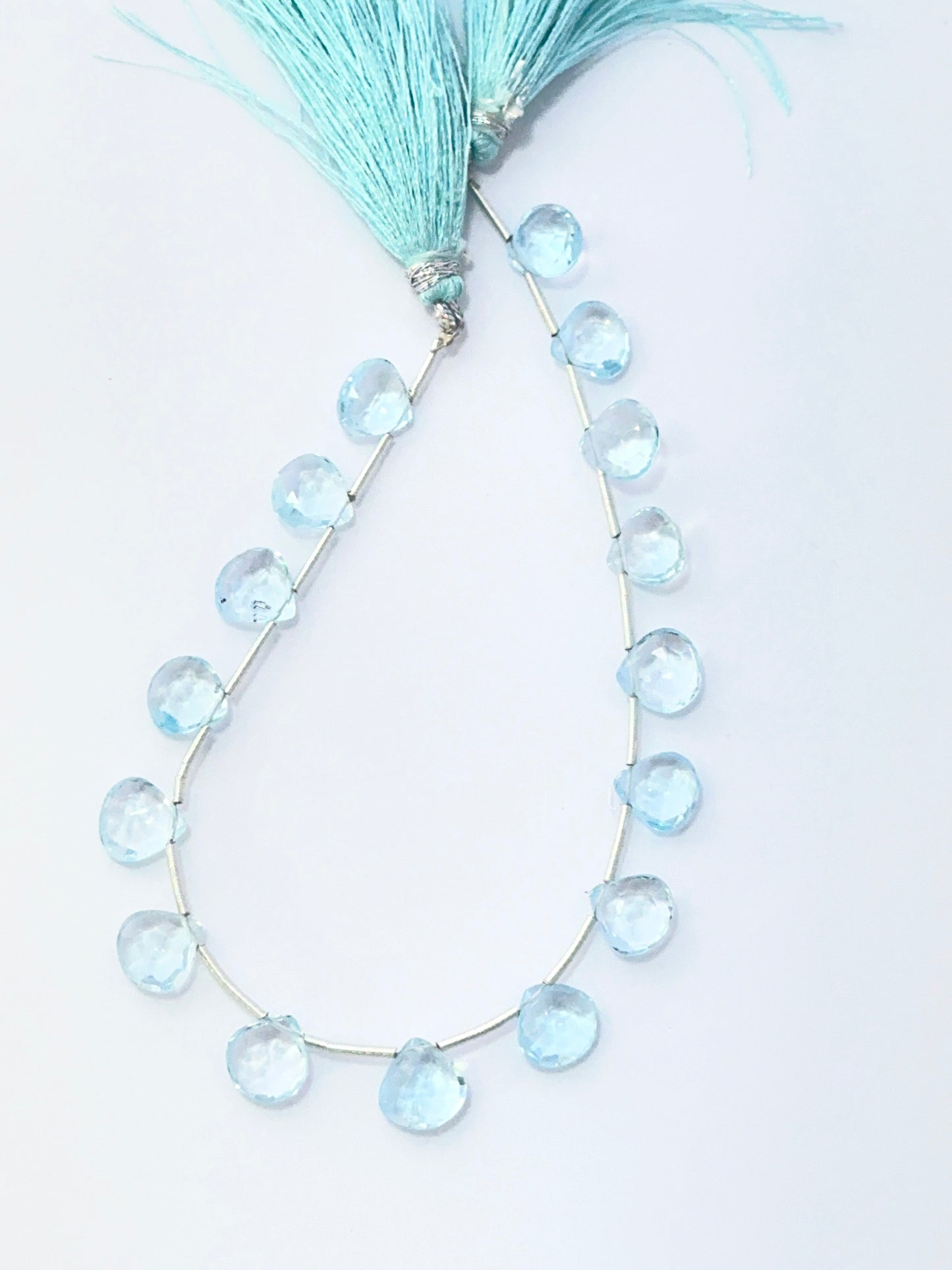 Close‑up of Sky Blue Topaz stone beads arranged in a strand with shimmering faceted surfaces.