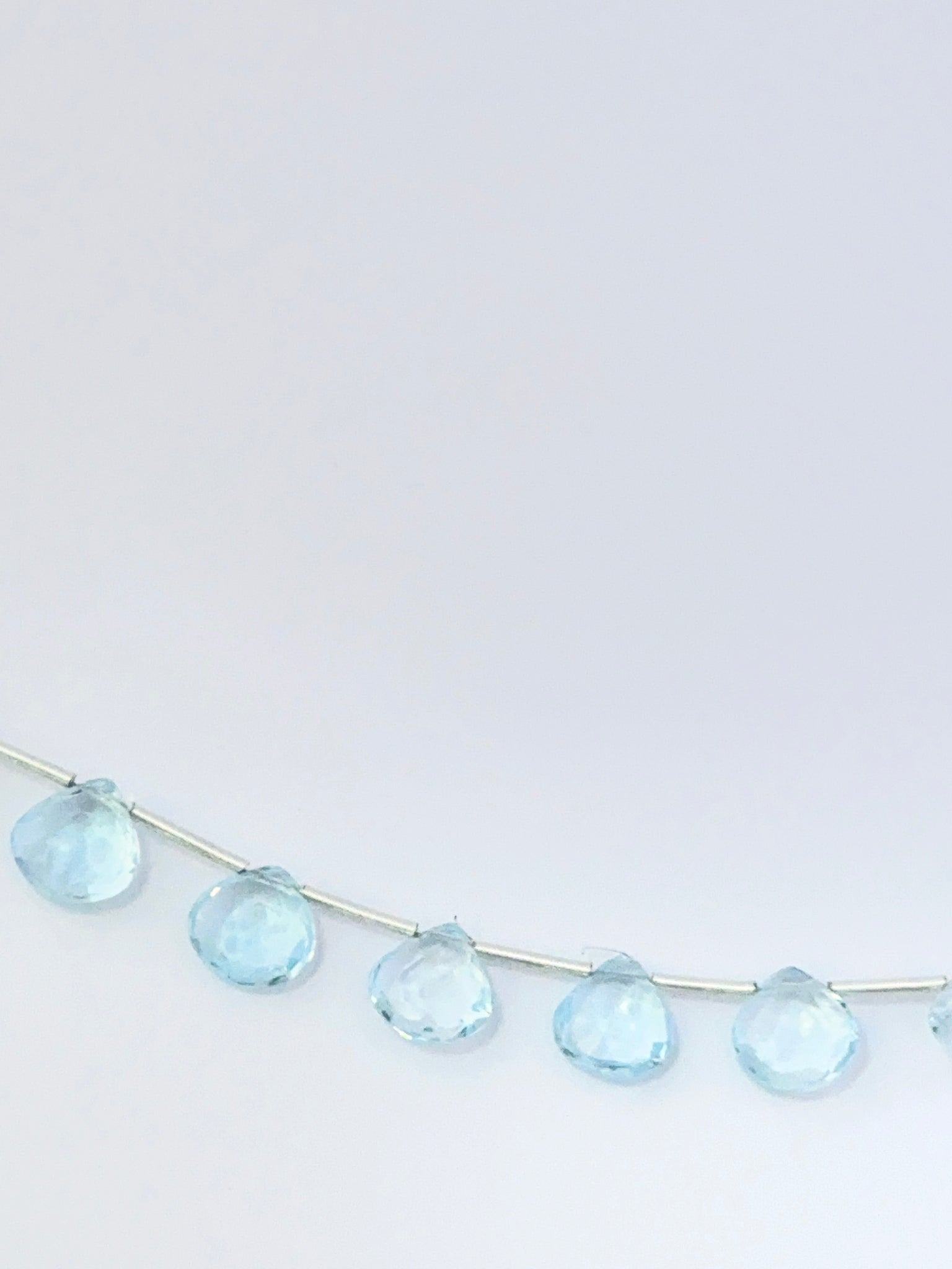 Stone beads made from Sky Blue Topaz showing polished briolette shapes and clear brilliance.