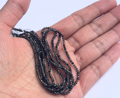 A person holds delicate strands of Smoky Quartz beads, showcasing their faceted design.
