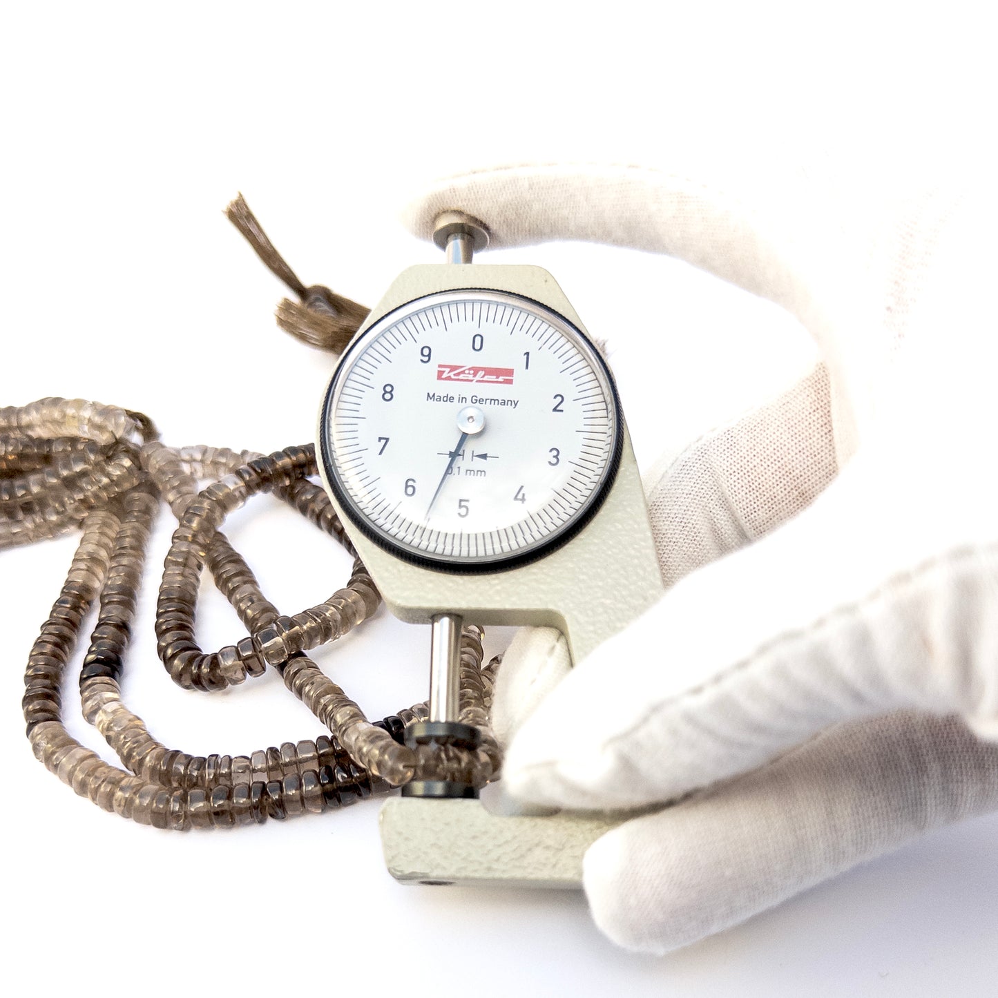 A dial gauge measures the Smoky Quartz smooth rondelle 4.5–6.7mm gemstone.