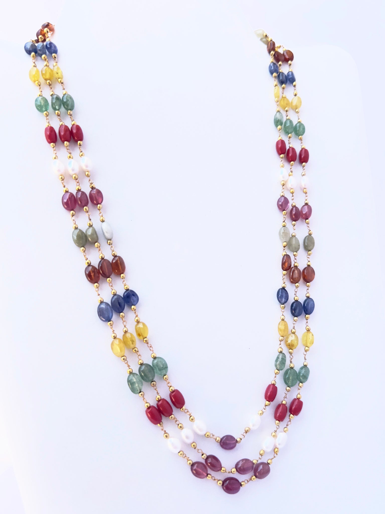 Close-up of Navratan gemstone beads, smooth oval cut, polished finish, arranged in strands.