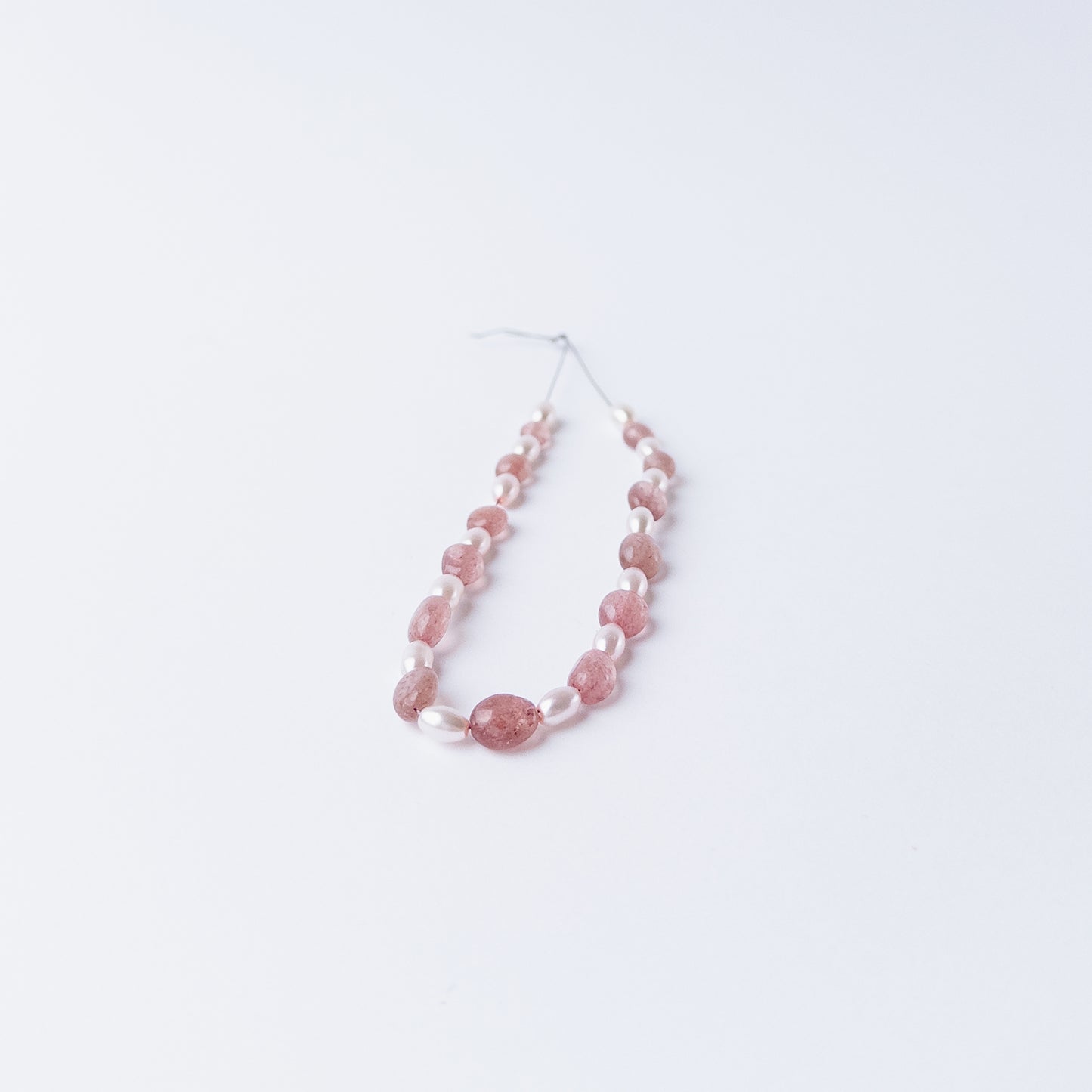 High quality Strawberry Quartz and Shell Pearl gemstone beads arranged for artisan beadwork.