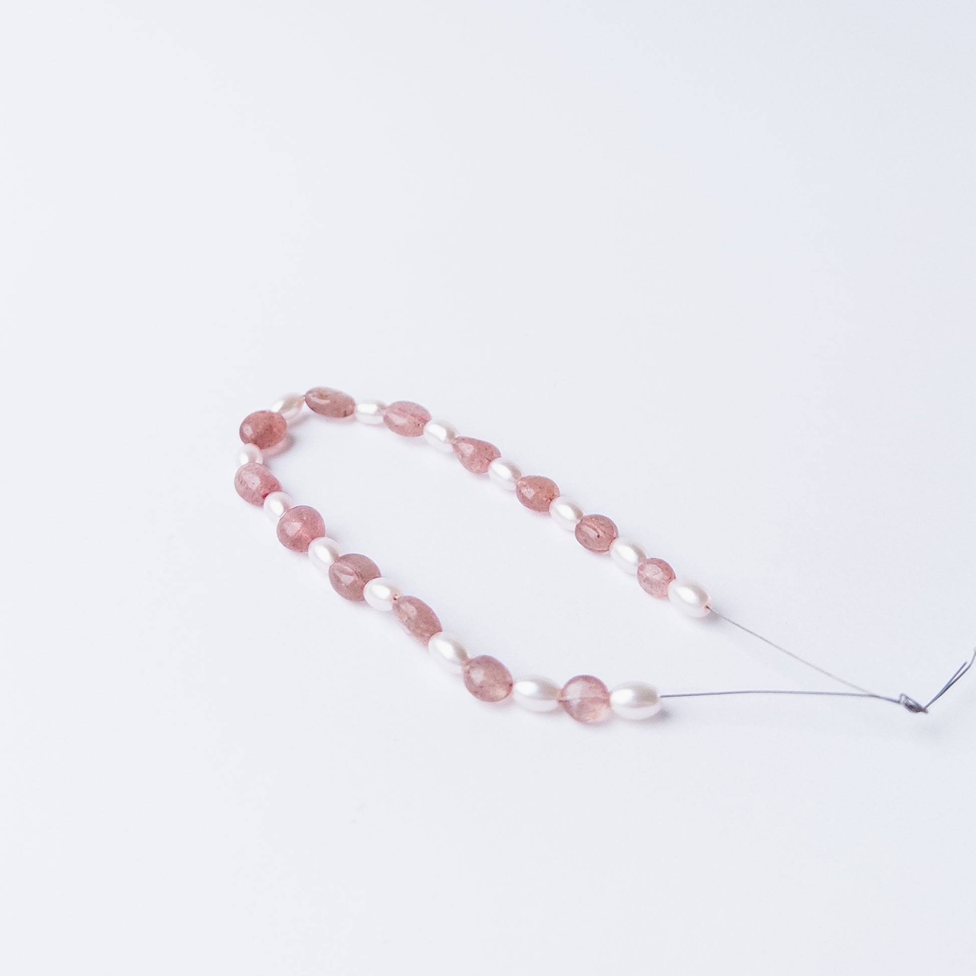 Close‑up of Strawberry Quartz and Shell Pearl beads highlighting their polished finish and shape.