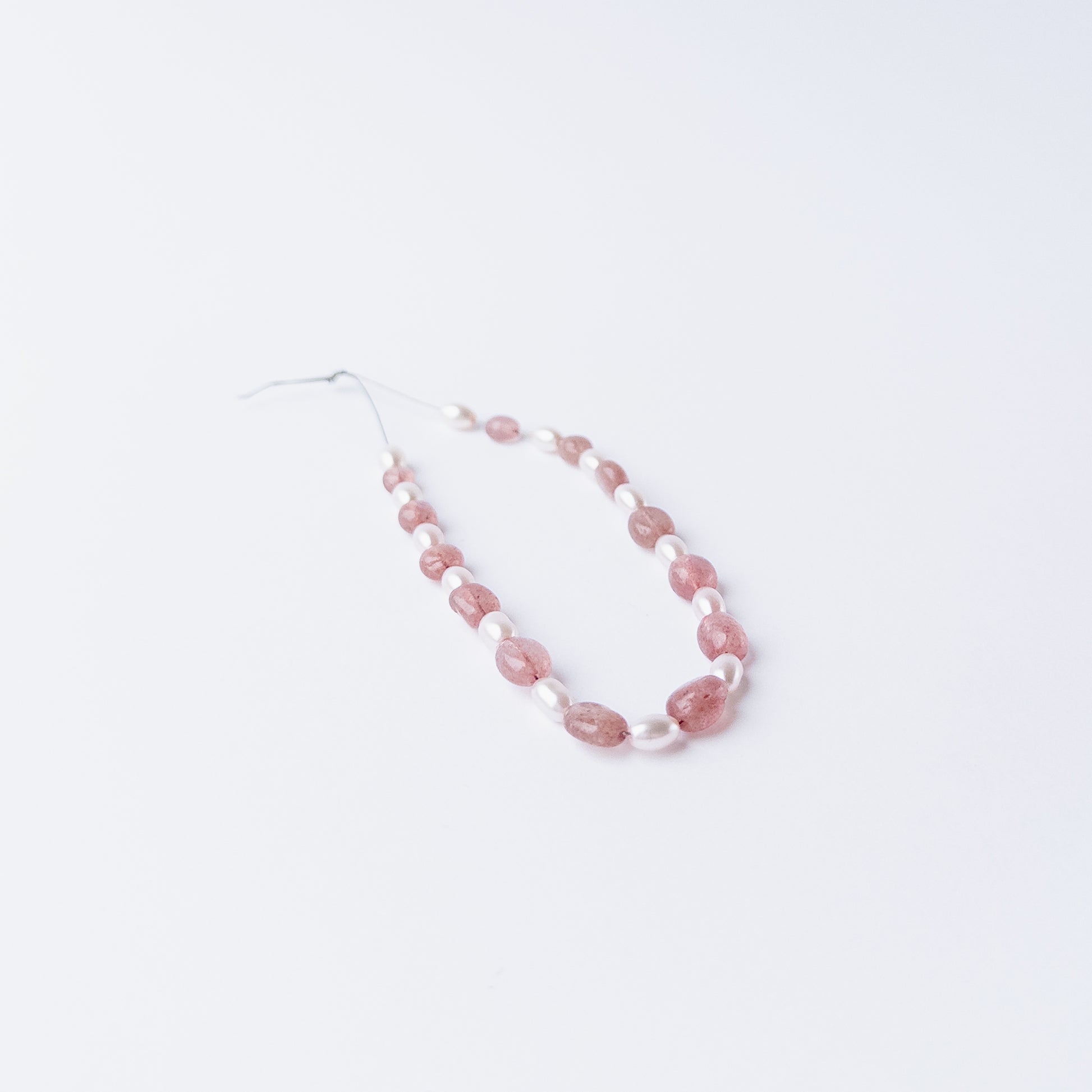 Strawberry Quartz and Shell Pearl gemstone beads arranged in a mixed set for DIY jewellery projects.