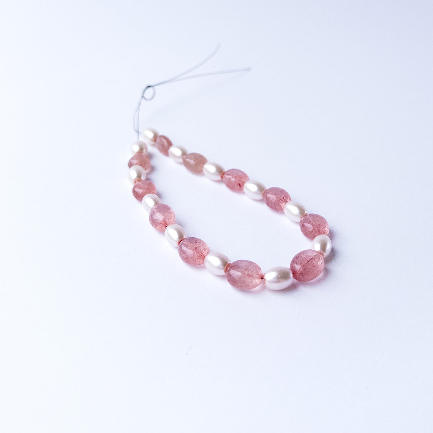 Strawberry Quartz and Shell Pearl smooth oval gemstone beads arranged neatly for DIY jewellery making.